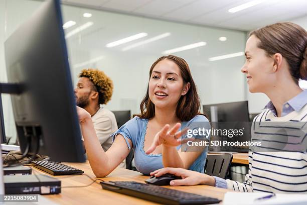 two young women students collaborate using laptop in classroom - computer lab stock pictures, royalty-free photos & images