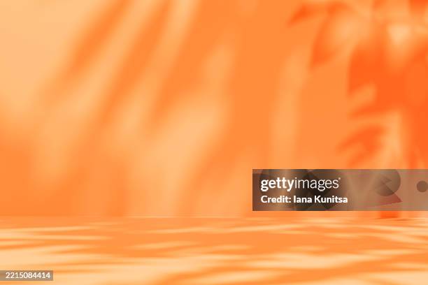 vivid orange color abstract 3d background with blurred natural shadows of leaves. minimalistic sunny backdrop for summer concepts, branding, presentations, designs. - iluminación gobo fotografías e imágenes de stock