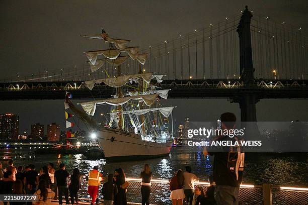 People watch as a Mexican Navy training ship is pulled away after it slammed into the nearby Brooklyn Bridge in New York on May 17, 2025. A Mexican...