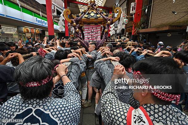 Participants carry a portable shrine or "mikoshi" as they take part in the annual Sanja Matsuri Festival in the Asakusa district of Tokyo on May 18,...