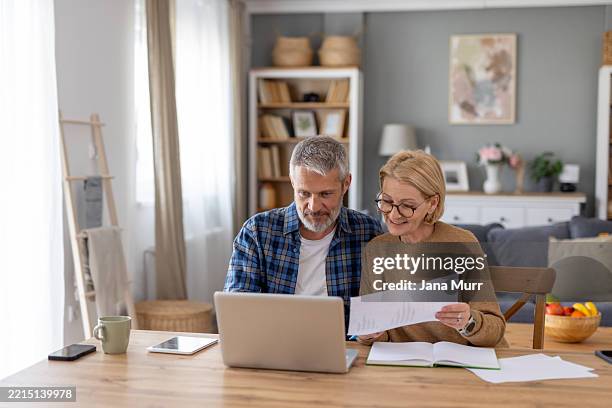 couple reviewing documents together at home office - couple arranging table stock pictures, royalty-free photos & images
