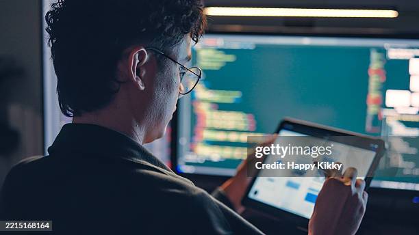 white man programmer or it specialist software developer with glasses working late into the night examining ux ui flowcharts and design wireframes for a mobile app,integrating design and development on dual monitors computer - web prototype stock pictures, royalty-free photos & images