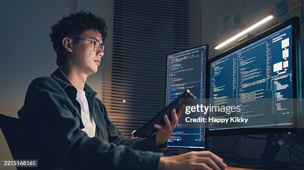 weißer mann programmierer oder it-spezialist softwareentwickler mit brille arbeitet bis spät in die nacht, um ux ui-flussdiagramme und design-wireframes für eine mobile app zu untersuchen und design und entwicklung auf einem computer mit zwei monitoren - webdesigner stock-fotos und bilder