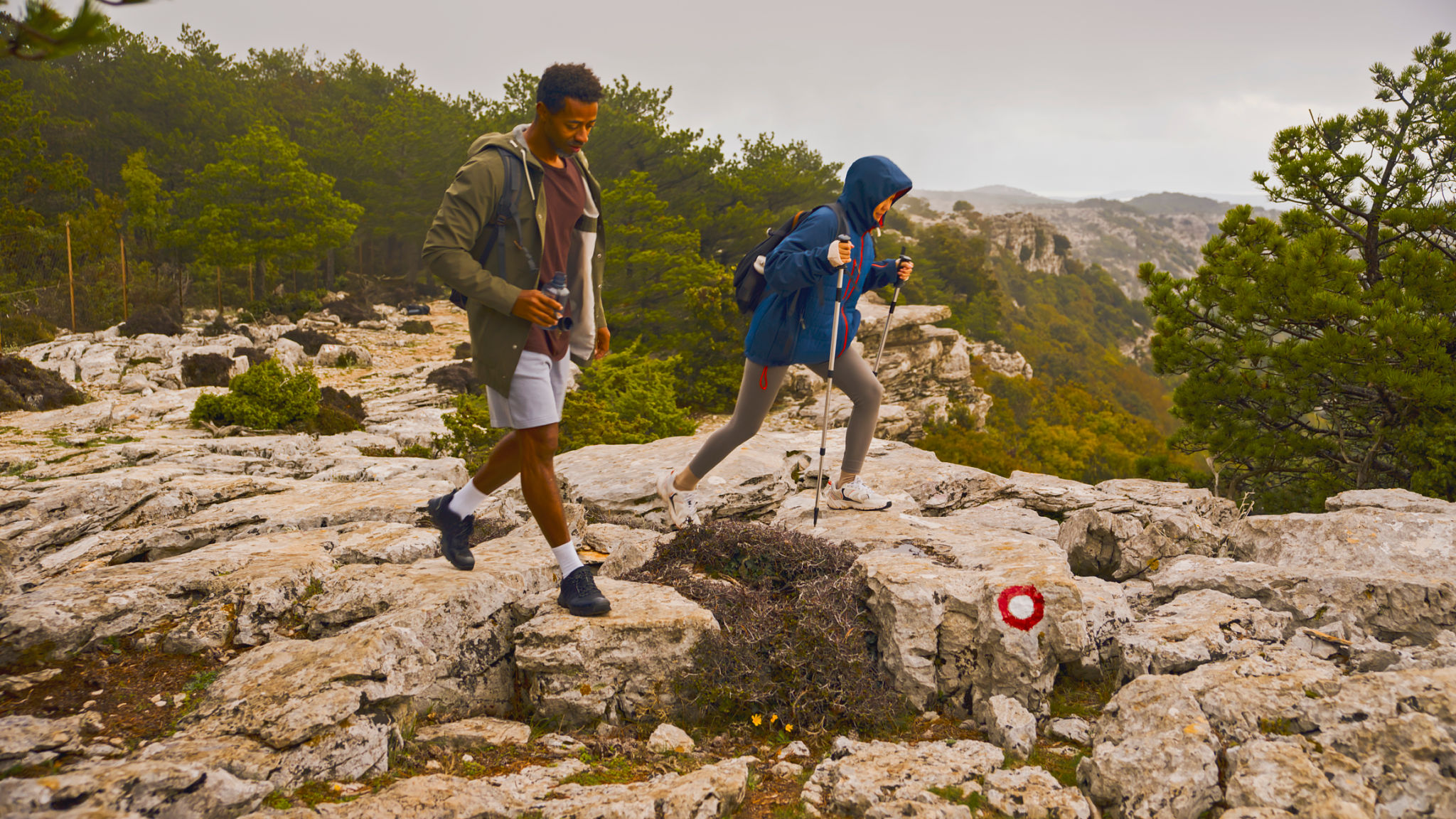 Mid-Adult Couple Navigating Rocky Mountain Trail During Overcast Day Mid-Adult Couple Navigating Rocky Mountain Trail During Overcast Day