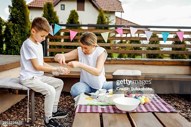 mother and son decorating eggs outdoors for easter celebration - easter hamper stock pictures, royalty-free photos & images