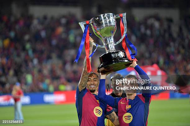 Barcelona's Brazilian forward Raphinha and Barcelona's Spanish midfielder Marc Casado raise their trophy as they celebrate their 28th Liga title...