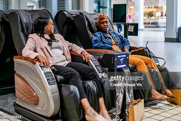 indigenous woman and friend in massage chairs - massagestuhl stock-fotos und bilder