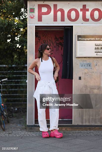 Sophia Geiss is seen wearing a dark brown crocheted bandana, silver hoop earrings, a silver nose ring, rectangular black sunglasses, a white tank...