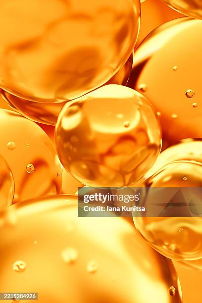 transparent yellow, orange color oil drops, bubbles, molecules. close-up. 3d vertical pattern. healthcare and medicine. cosmetic products for skin care. citrus. vitamin c. - lubricación fotografías e imágenes de stock