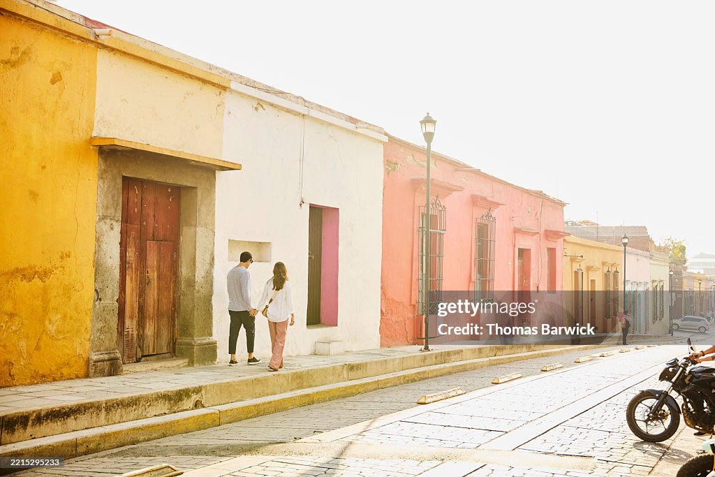 Extreme wide shot relaxed couple walking on city street in Mexico