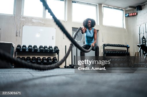 Determined Mid Adult Black Woman Training with Battle Ropes in a Bright Gym Determined Mid Adult Black Woman Training with Battle Ropes in a Bright Gym