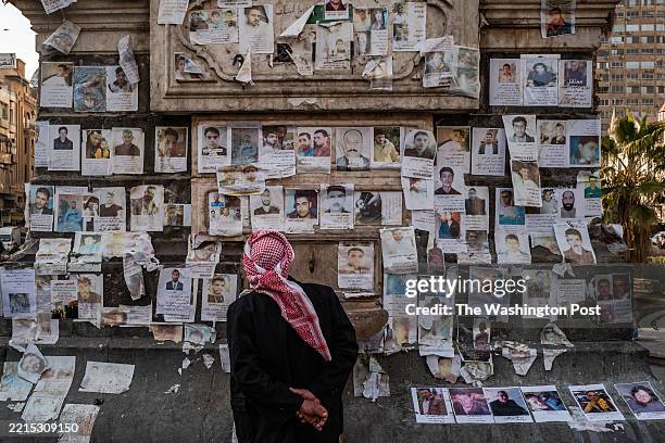 Man looks at photos of missing people at the Al Marjeh Square, known as the Martyrs' Square, in Damascus, Syria, Friday, January 17, 2025.