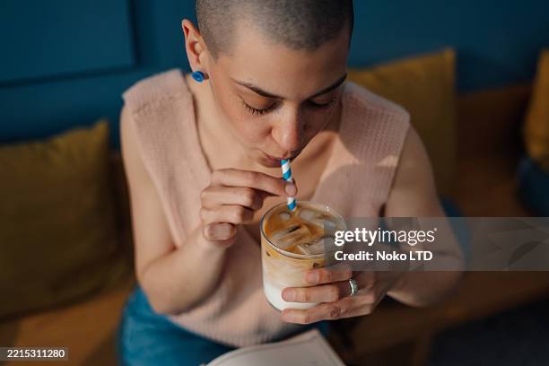 young woman enjoying iced coffee in a cafe - iced coffee stock pictures, royalty-free photos & images
