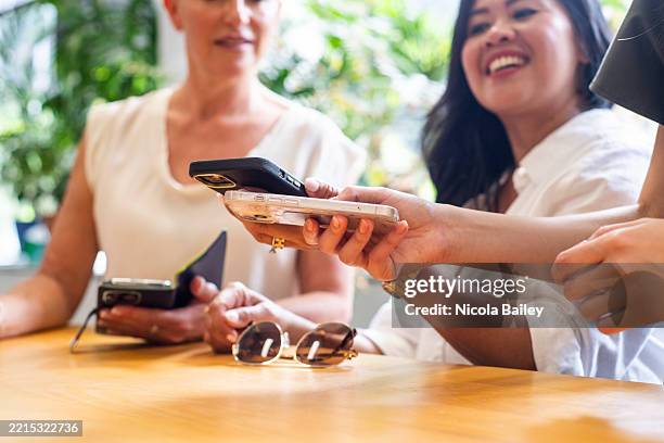 three people touch phones together - kabelloses-laden-von-gerät-zu-gerät stock-fotos und bilder
