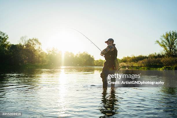 scène paisible de pêche à la mouche avec un homme d’âge moyen au coucher du soleil. - pêcheur photos et images de collection