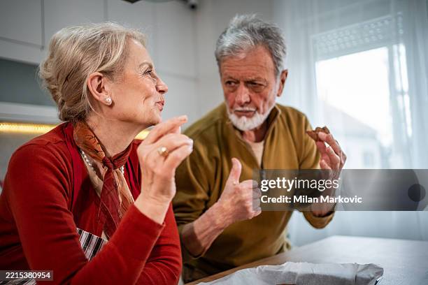 couple de personnes âgées dégustant des biscuits fraîchement cuits dans la cuisine - repas servi photos et images de collection