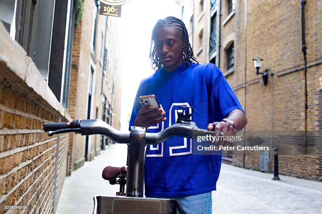 One young man using a smart phone to hire a city bicycle