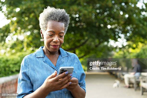 woman using startphone on tree lined path - medium shot stock pictures, royalty-free photos & images