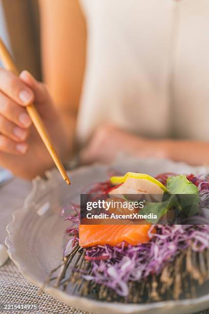 detail of young woman eating sushi at tropical cafe - sashimi stock pictures, royalty-free photos & images