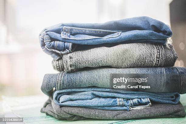 stack of folded denim jeans textile background - denim pants stock pictures, royalty-free photos & images