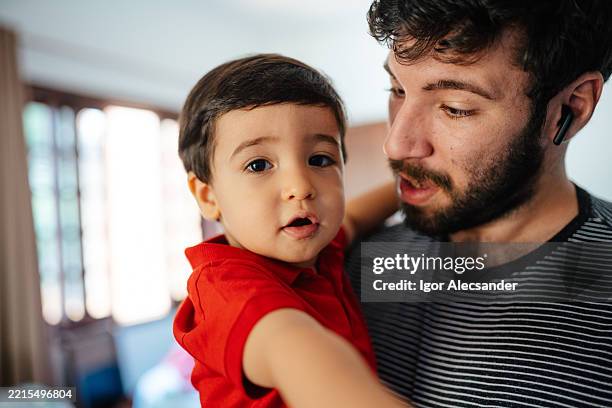 father holding baby boy at home - een dag uit het leven serie stockfoto's en -beelden