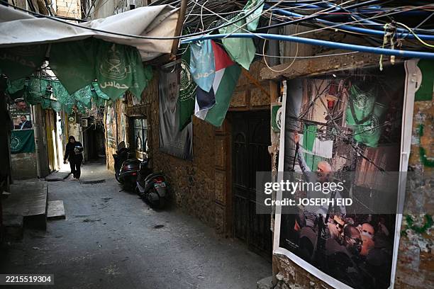 Woman walks past portraits of Palestinian Hamas movement's slain political chief Ismail Haniyeh in a narrow alleyway at the Burj al Barajneh camp for...