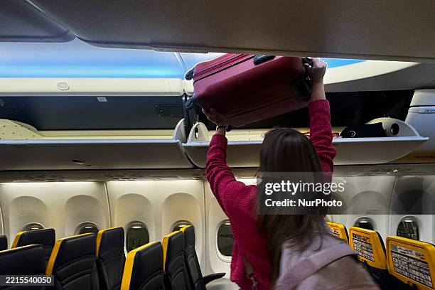 Person stacks luggages in an overhead bin at plane at the airport in Treviso, Italy on May 19, 2025.