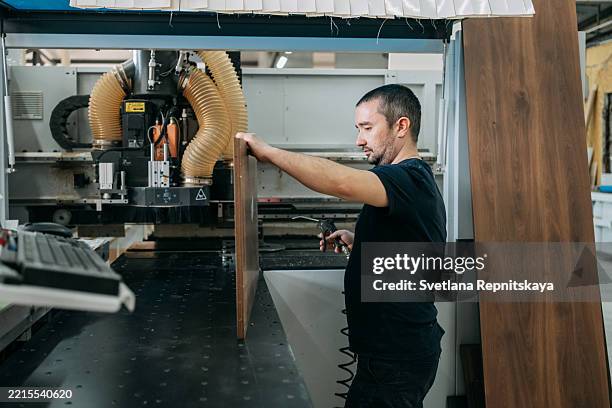 carpenter cleaning wood panel with air gun after processing on cnc machine - moulding machine stock pictures, royalty-free photos & images