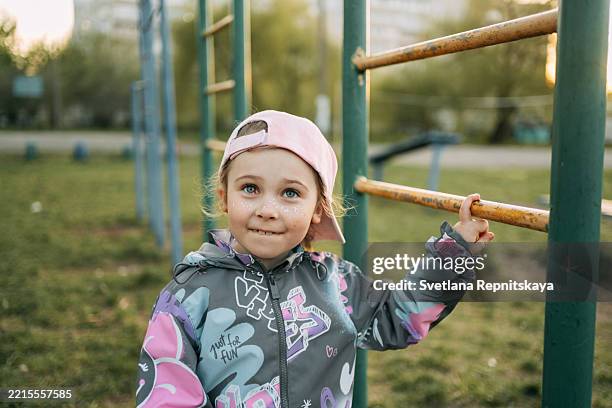 smiling girl with cochlear implant playing on monkey bars in playground - cute light skin girls stock pictures, royalty-free photos & images