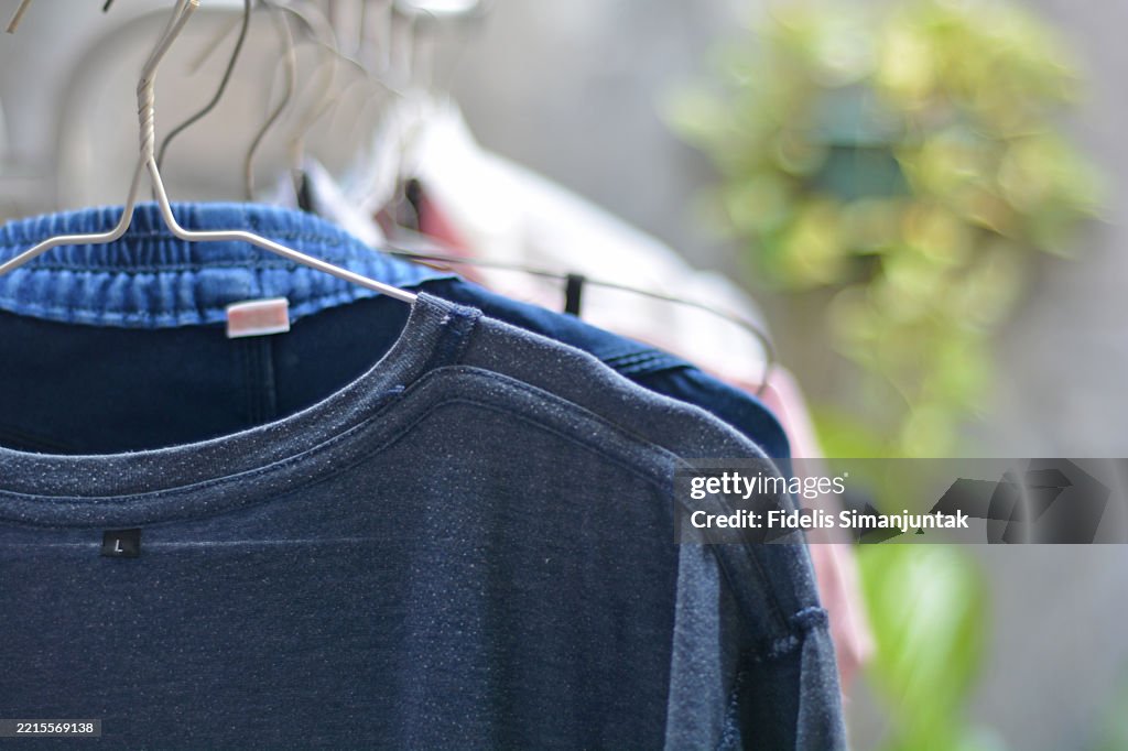 Colorful Shirts and Trousers Hanging on Hangers to Dry Outdoors