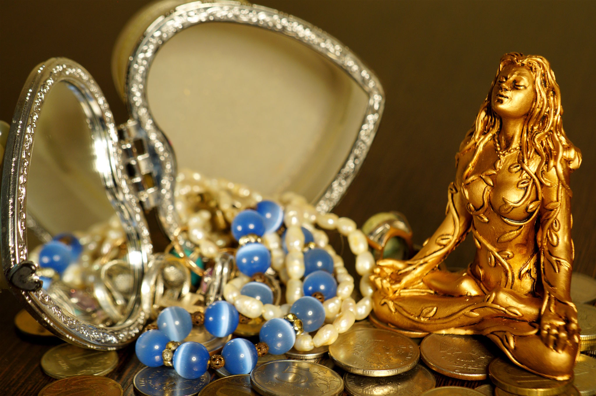 A female Buddha statuette with jewelry and coins. A female Buddha statuette with jewelry and coins.