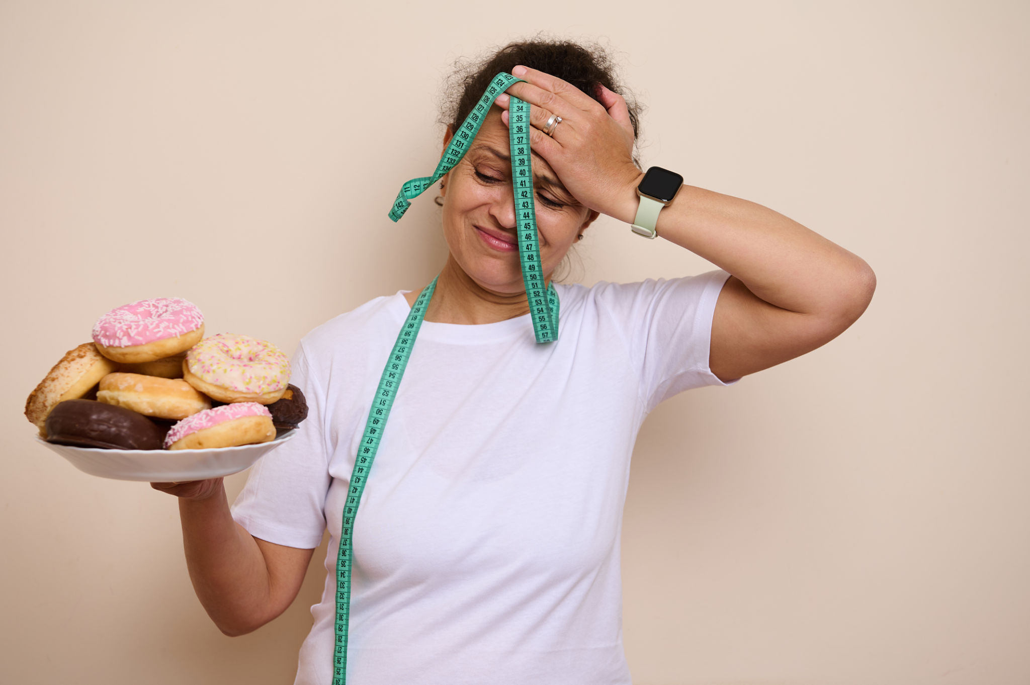 Woman Struggles With Healthy Choices, Holding Donuts and Measuring Tape Woman Struggles With Healthy Choices, Holding Donuts and Measuring Tape