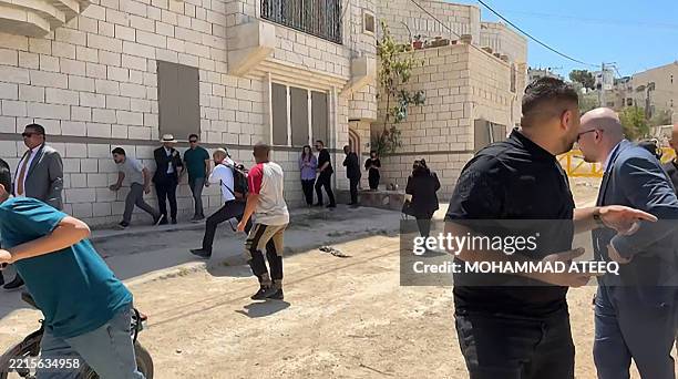This frame grab from AFPTV footage shows members of a diplomatic delegation from the European Union reacting after shots were fired as they gathered...