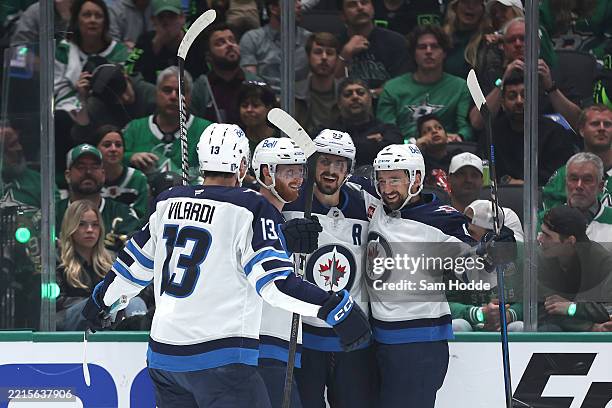 Mark Scheifele of the Winnipeg Jets celebrates with Gabriel Vilardi, Kyle Connor and Neal Pionk after scoring a goal on Jake Oettinger of the Dallas...