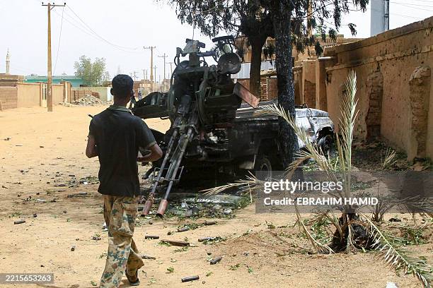 Sudanese army soldier walks toward a truck-mounted gun left behind by the paramilitary Rapid Support Forces , in Salha, south of Omdurman, a day...