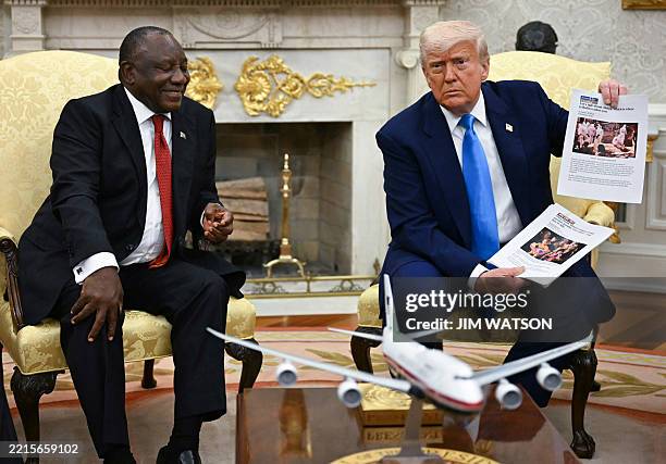 President Donald Trump shows pictures as he meets with South African President Cyril Ramaphosa in the Oval Office of the White House in Washington,...