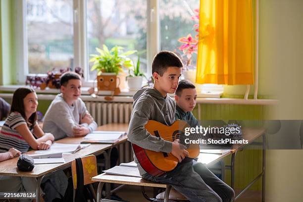 the boy plays the guitar in class. - education-building stock pictures, royalty-free photos & images