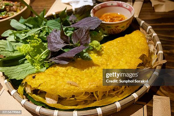 a dish of vietnamese pancake or bánh xèo tôm thịt shows its crispy shell filled with shrimp, pork, and bean sprouts, vietnam. - savory stock-fotos und bilder