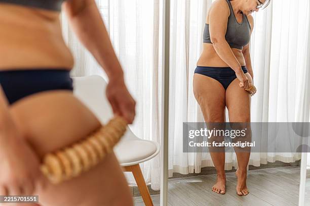 plus size woman applying anti cellulite madero therapy on her thighs. maderotherapy anticellulite massage treatment - cellulite stock pictures, royalty-free photos & images