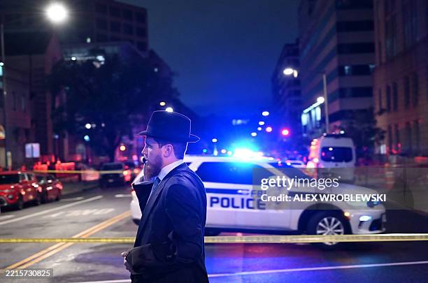Man, standing behind police tape, talks on his cell phone outside the Capital Jewish Museum following a shooting that left two people dead, in...