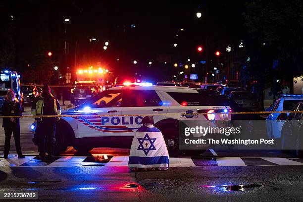 Bystander prays while wearing an Israel flag with a cross in the middle, near the Capital Jewish Museum near the U.S. Capitol on May 21, 2025 in...