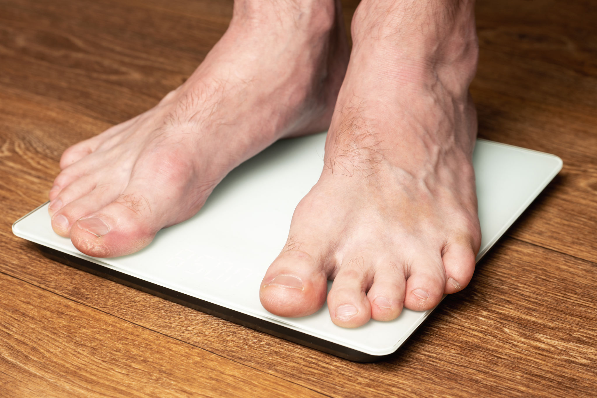 A man measures his weight by standing on a floor scale A man measures his weight by standing on a floor scale