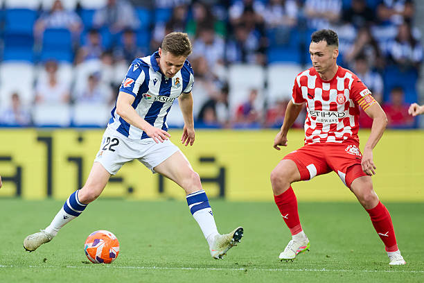 Benat Turrientes of Real Sociedad competes for the ball with Arnau Martinez of Girona FC during the LaLiga EA Sports match between Real Sociedad and...