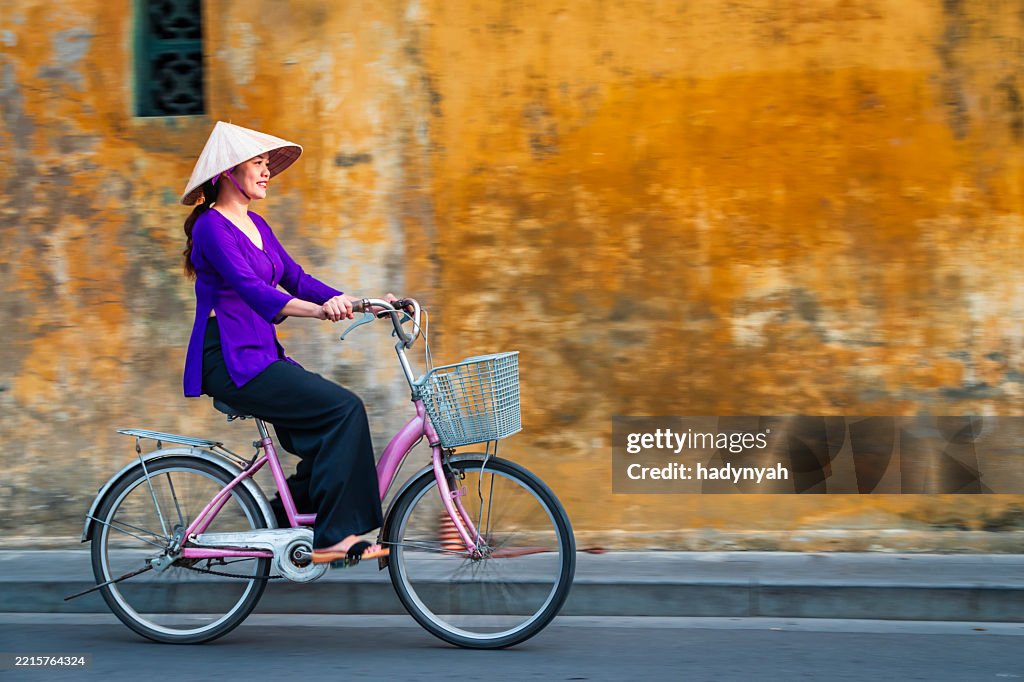 Vietnamese woman with a bicycle, old town in Hoi An city, Vietnam
