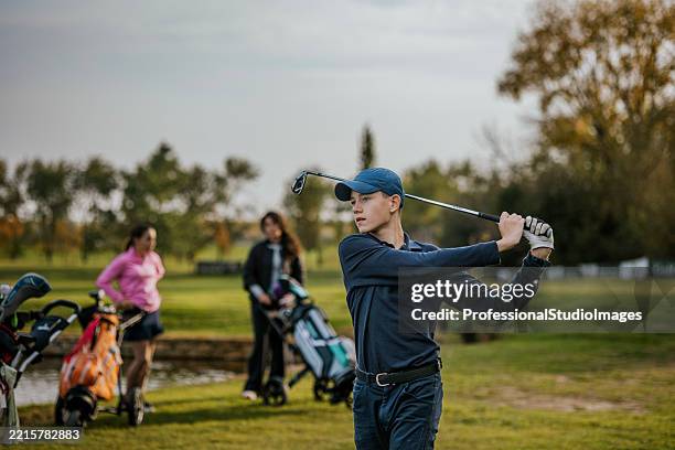 young golfer making a swing on a sunny golf course - golf swing stock pictures, royalty-free photos & images