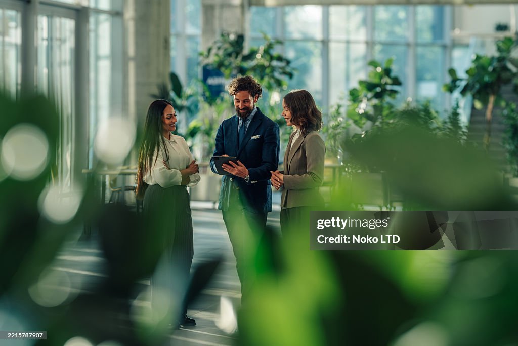 Businesspeople using digital tablet in modern office building lobby