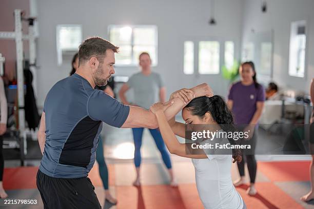 women's self-defense class with instructor demonstrating techniques - self defence stock pictures, royalty-free photos & images