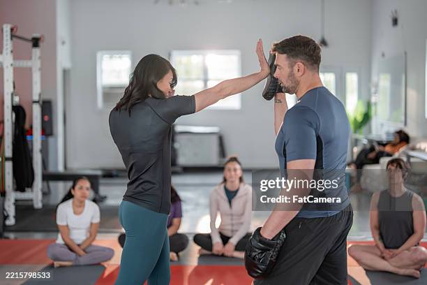 women's self-defense class demonstrating techniques with instructor - artes marciais imagens e fotografias de stock