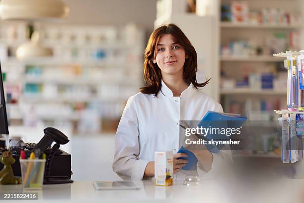 smiling female pharmacist working in a drug store. - apotheker stockfoto's en -beelden