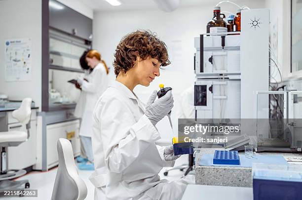 young laboratory researcher in white coat conducting scientific analysis with precision equipment - amostra médica imagens e fotografias de stock